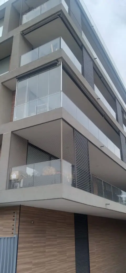 Edificio de departamentos con balcones y antepechos de vidrio