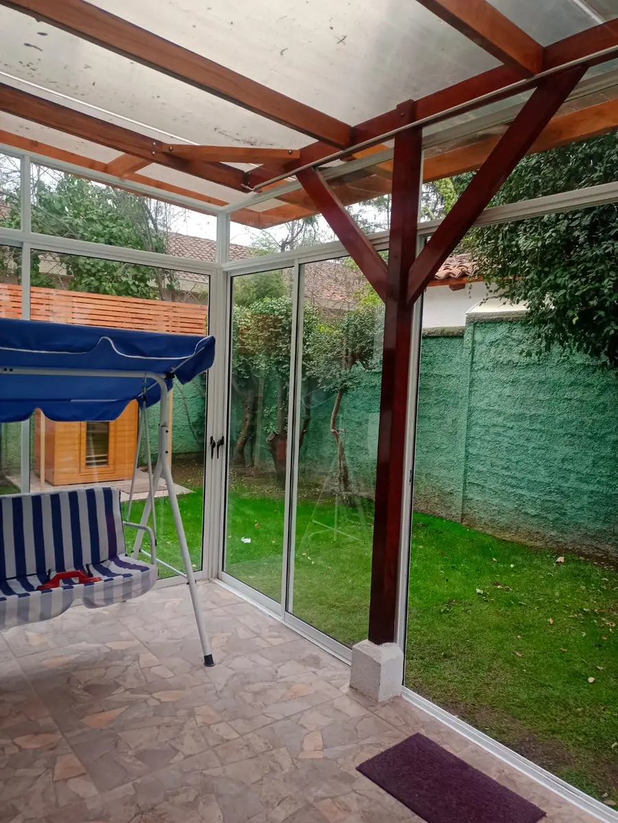 Interior de una terraza cerrada con vidrio bajo un techo de madera