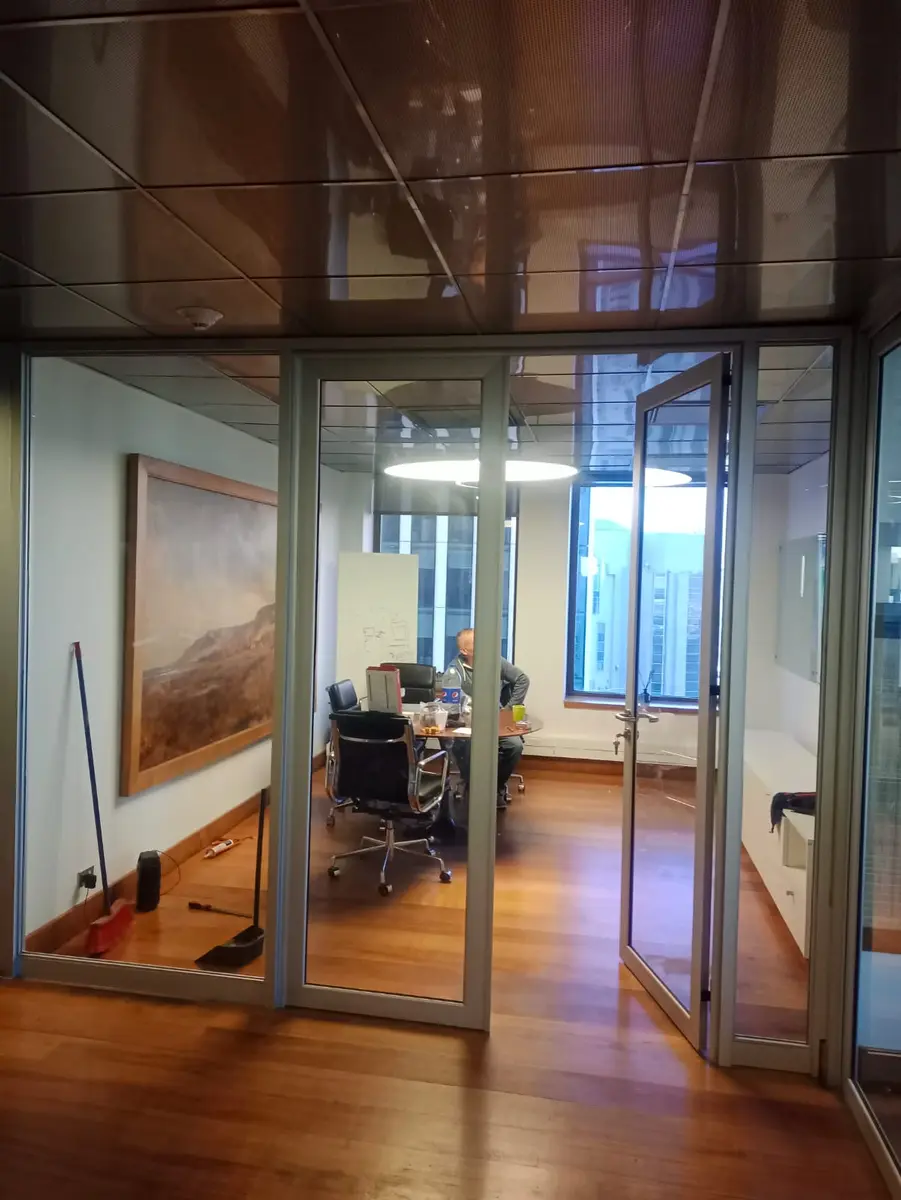 Oficina privada con división de vidrio y puerta batiente con perfil de aluminio
