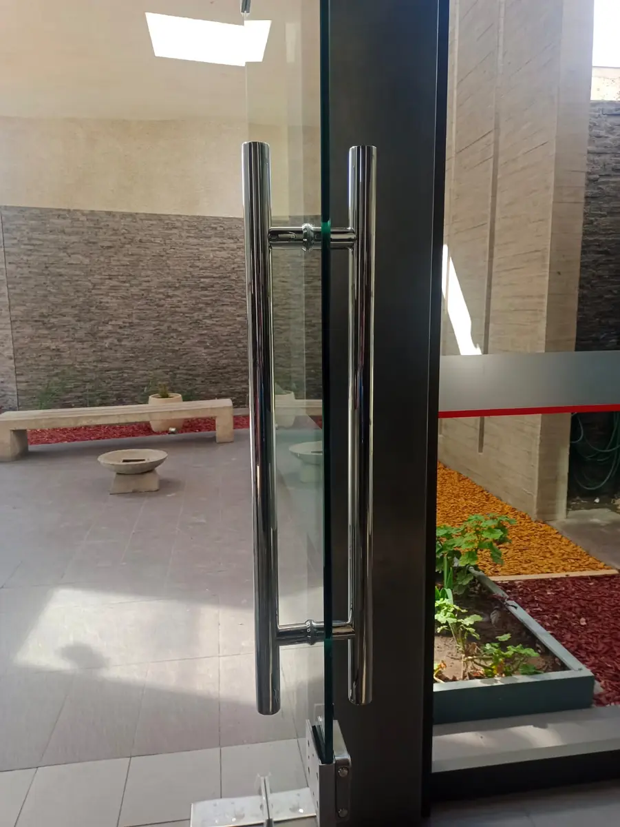 Puerta de vidrio templado con tirador de acero en un acceso comercial