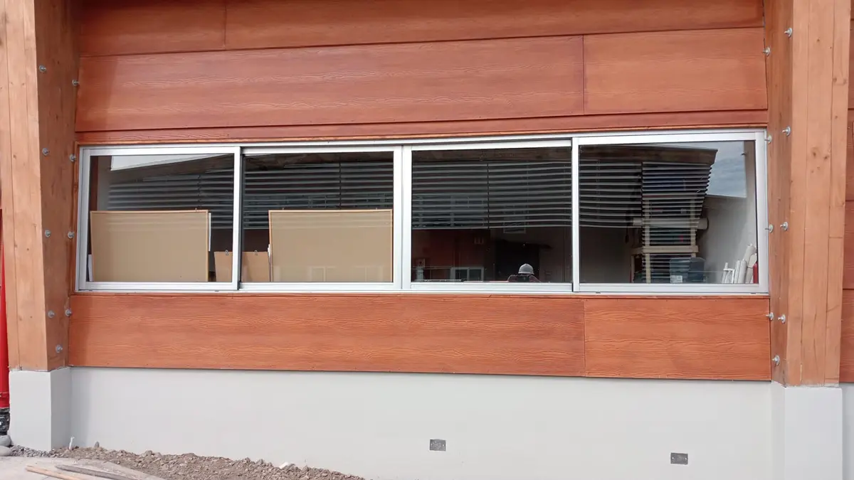 Ventana corredera de aluminio instalada en un muro revestido en madera