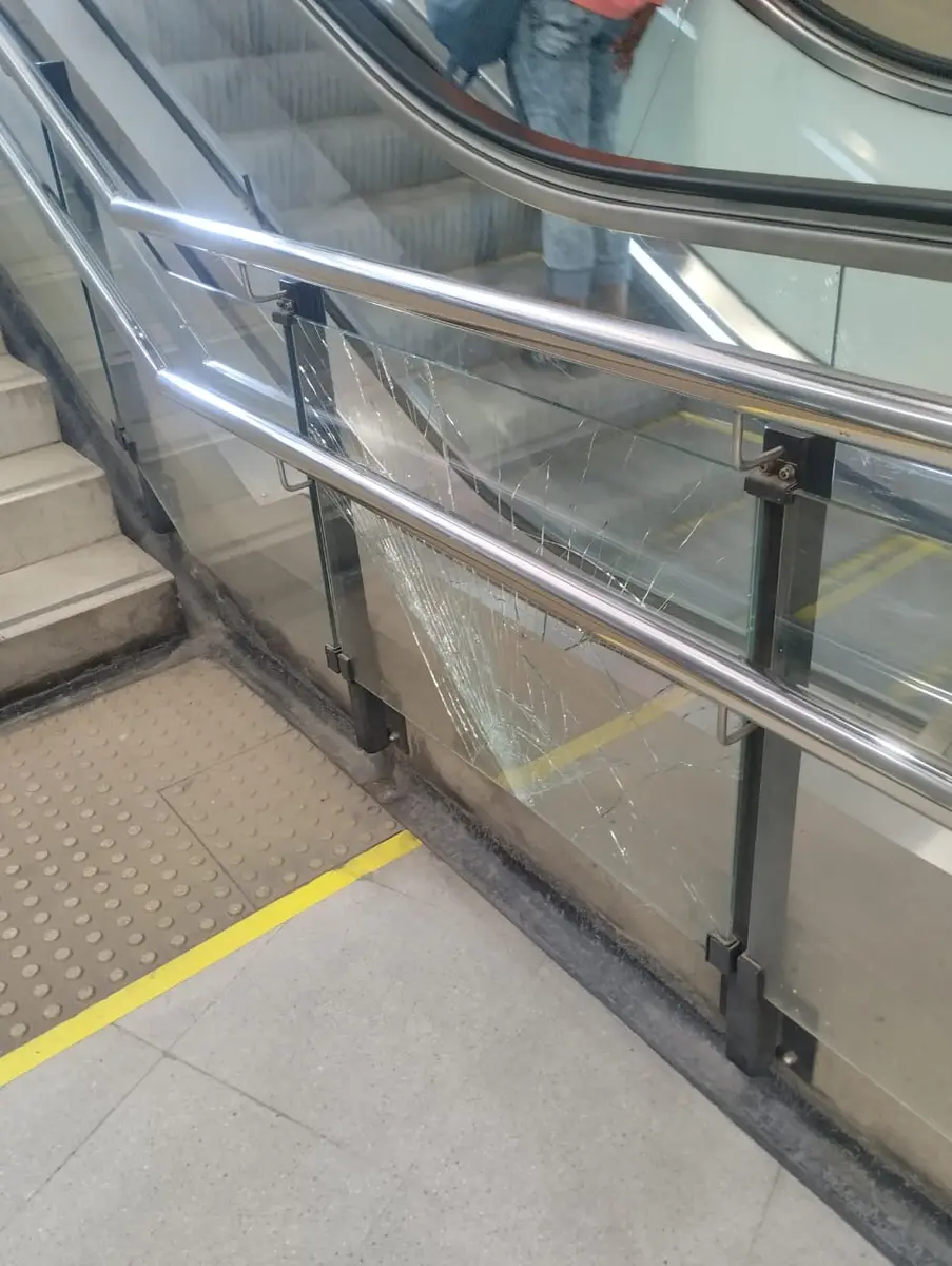 Panel de vidrio quebrado en una baranda con pasamanos de acero